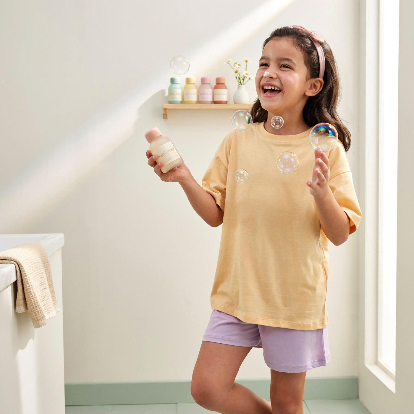 A happy girl holding a Mini Muse bottle with bubbles around her